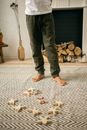 Crop faceless kid standing near scattered wooden toys at home
