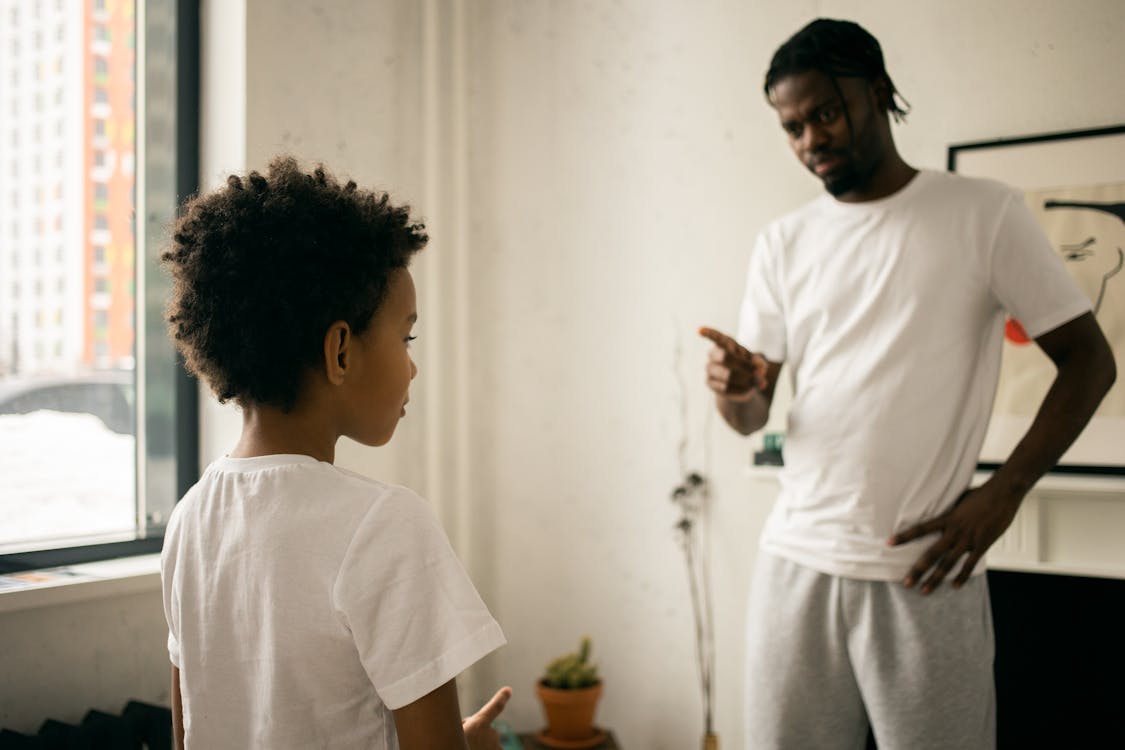 Young black father edifying calm son at home