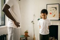 Crop unrecognizable black father standing with hands on waist and scolding confused son