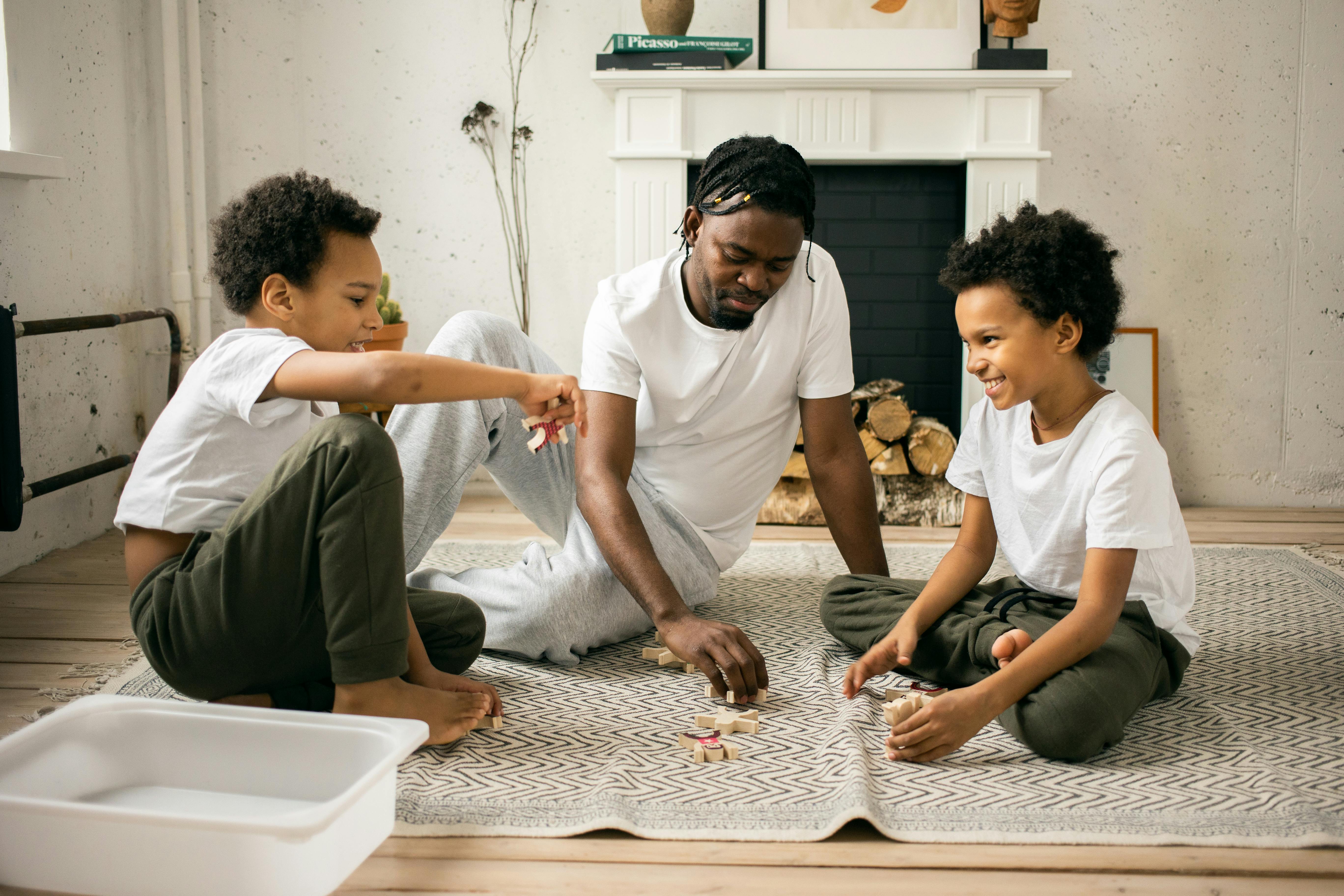 positive ethnic boys with father playing on floor at home