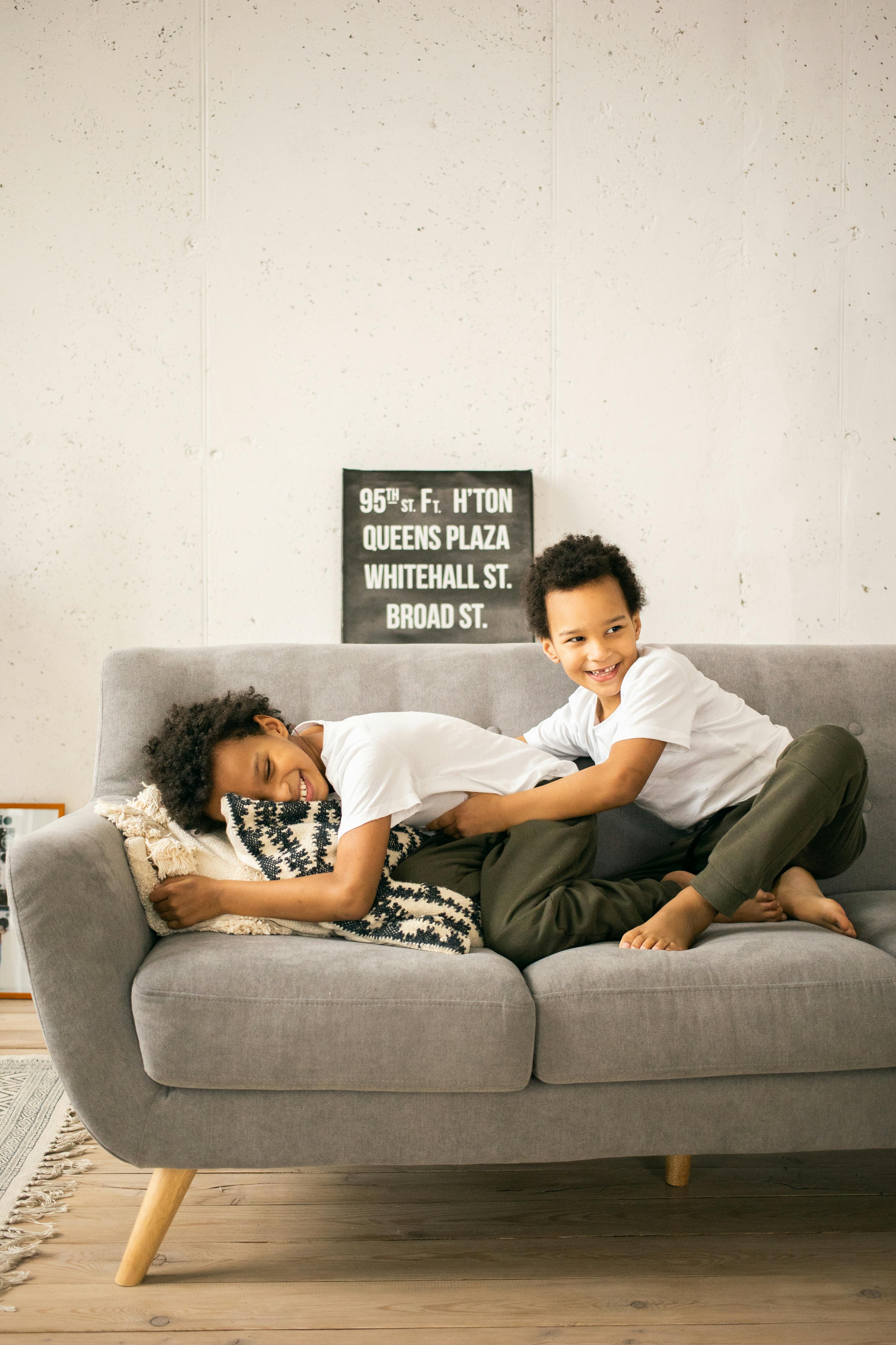 positive black boys sitting on sofa in living room in daytime