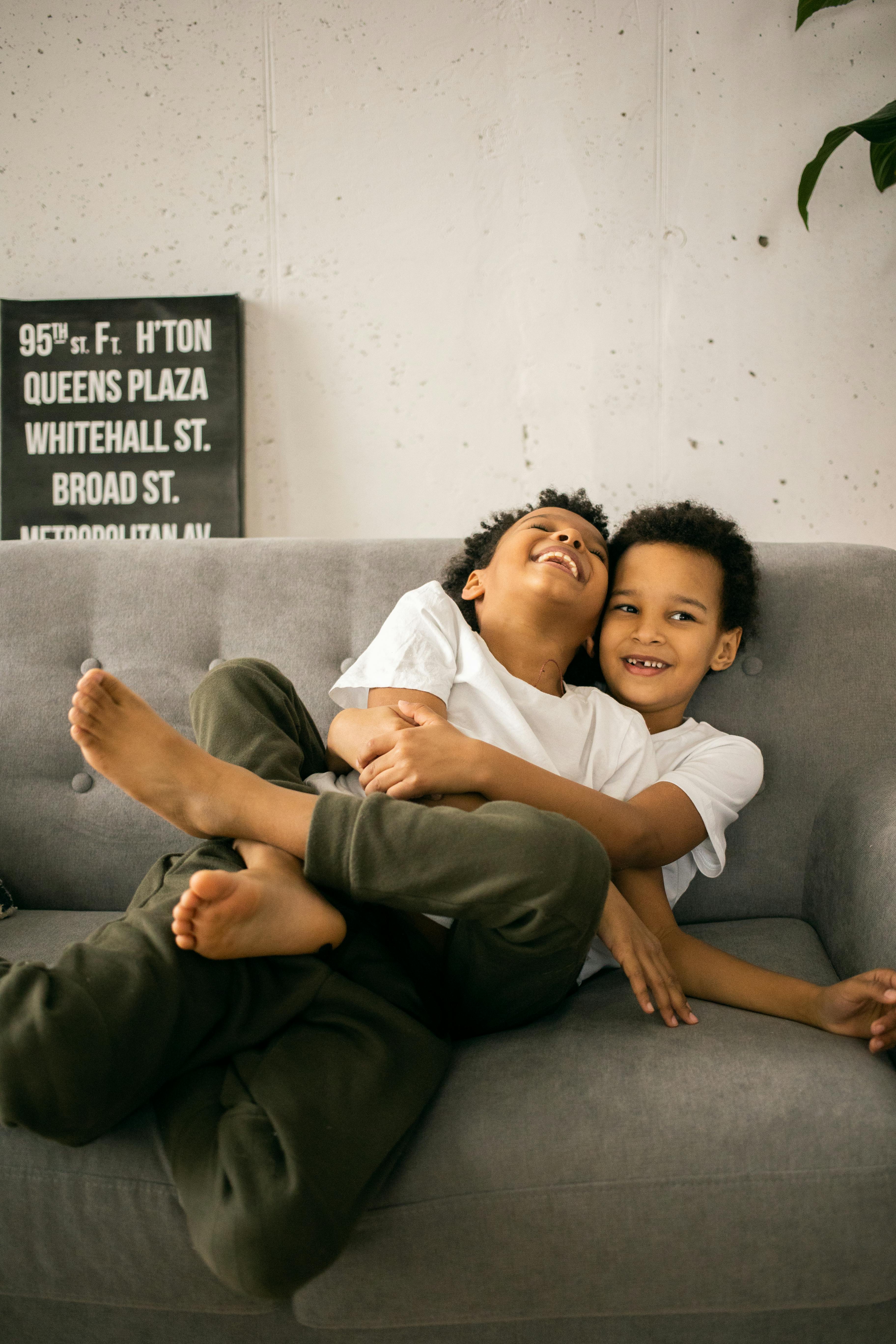 positive black boys sitting on sofa and embracing in light room