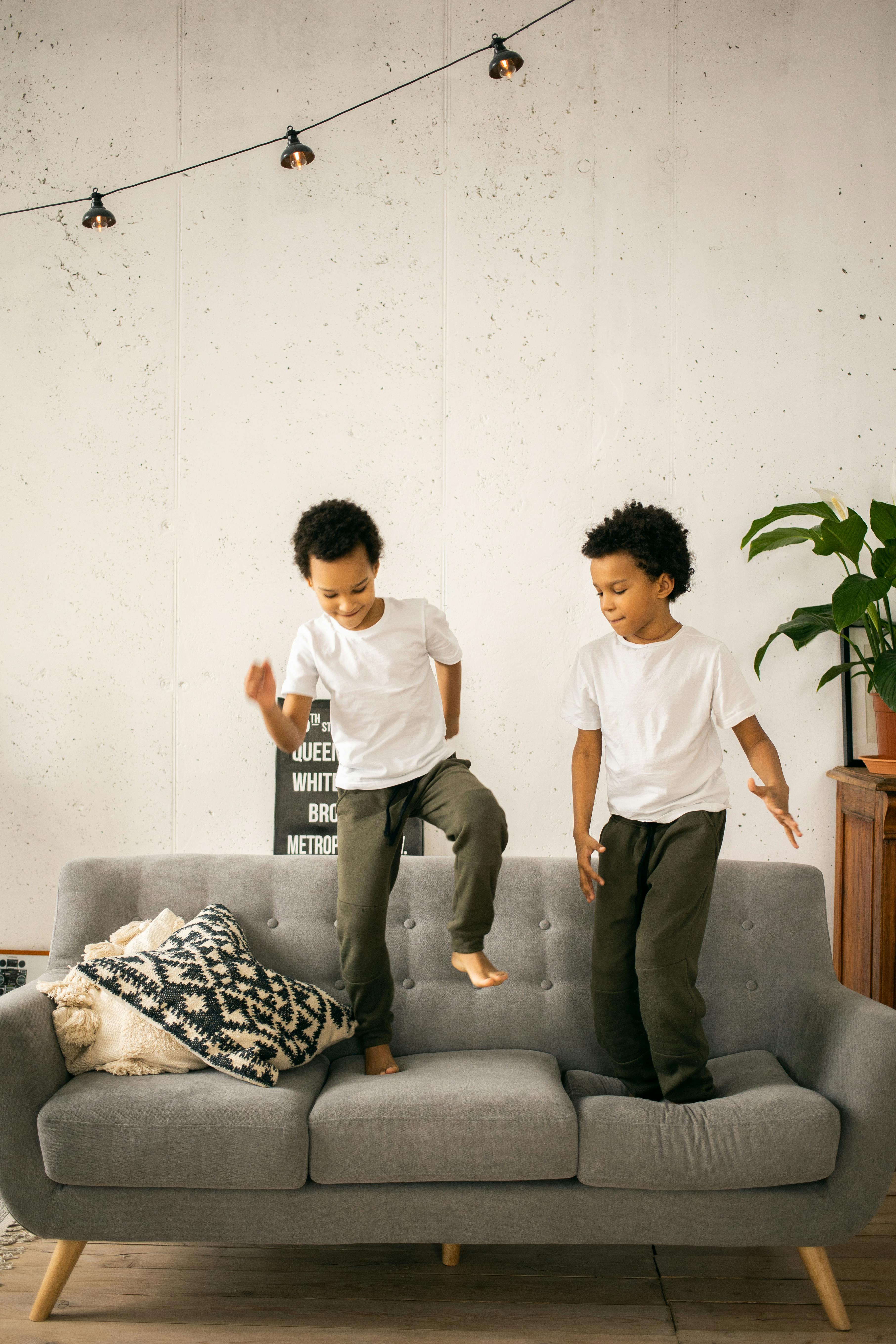 black brothers standing on sofa in living room