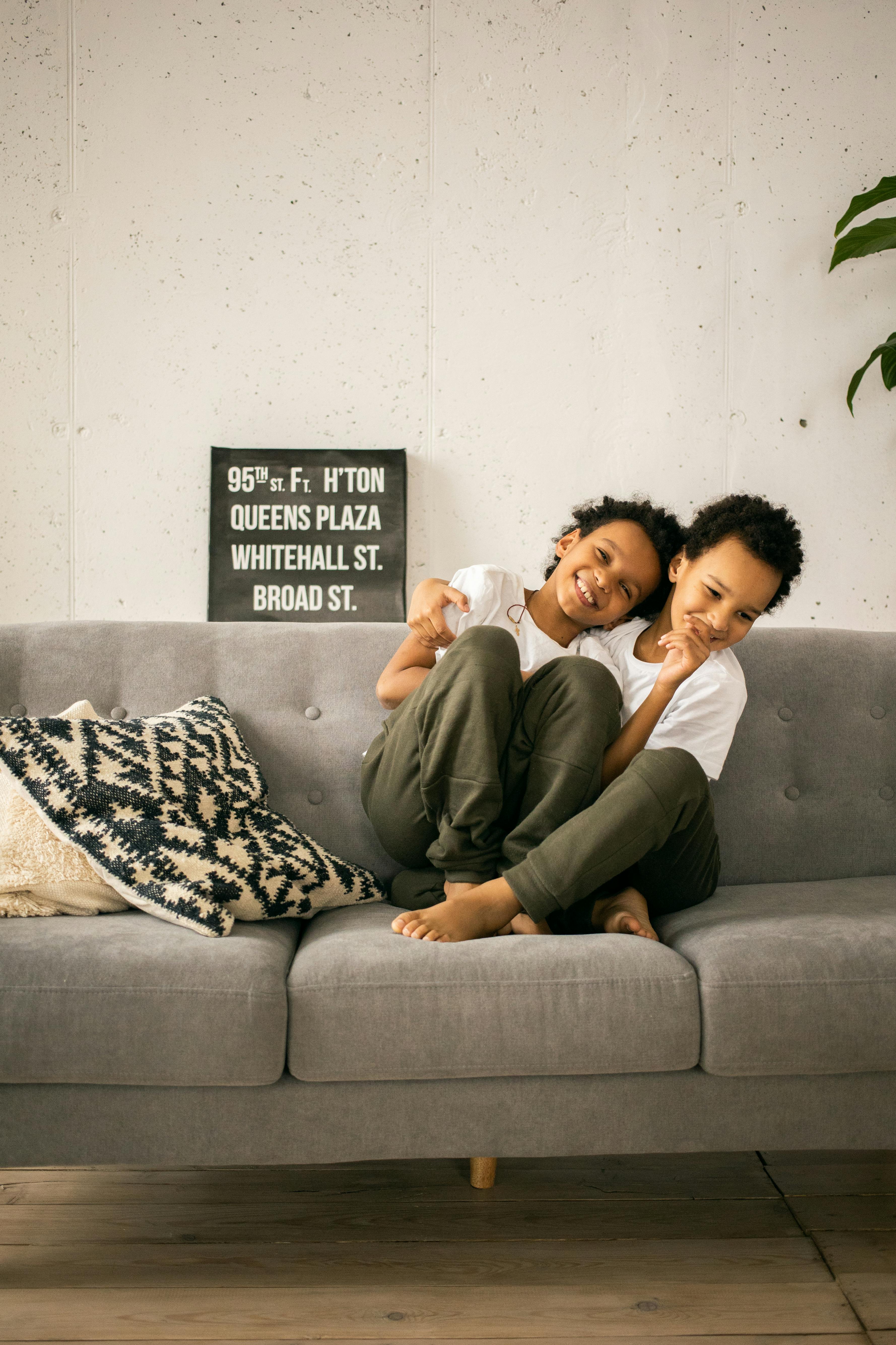 positive black brothers sitting on sofa in room