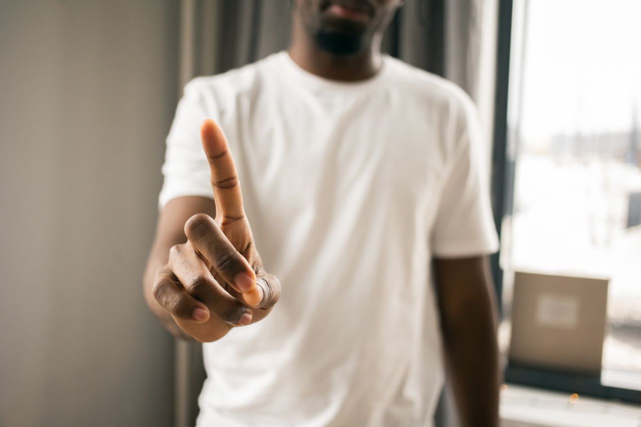 crop anonymous african american male in white t shirt showing stop ges
