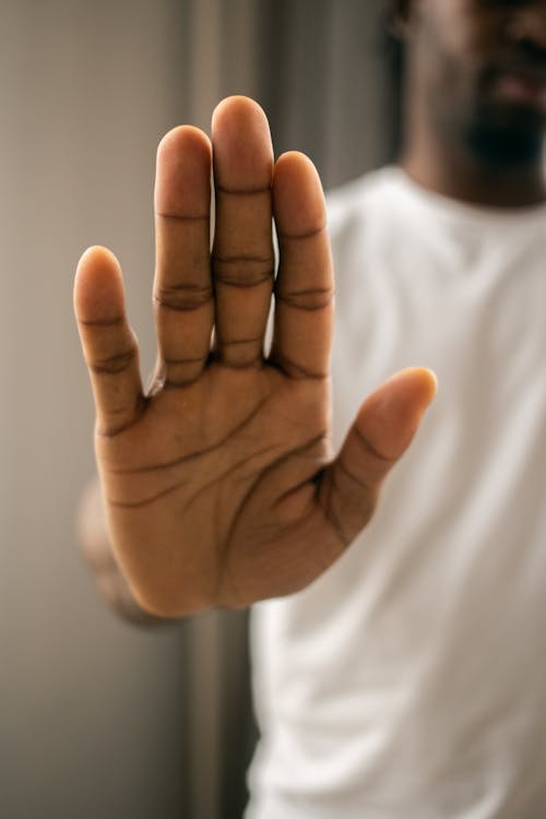 Faceless black man showing stop gesture with hand