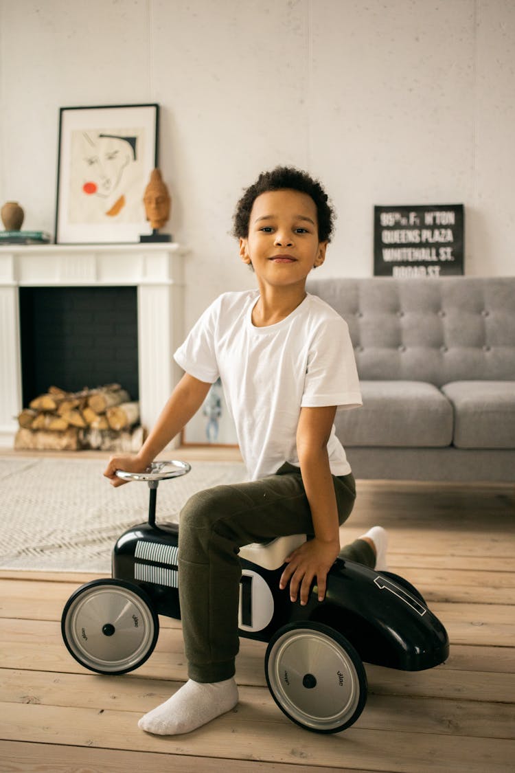 Cheerful Black Boy On Toy Car