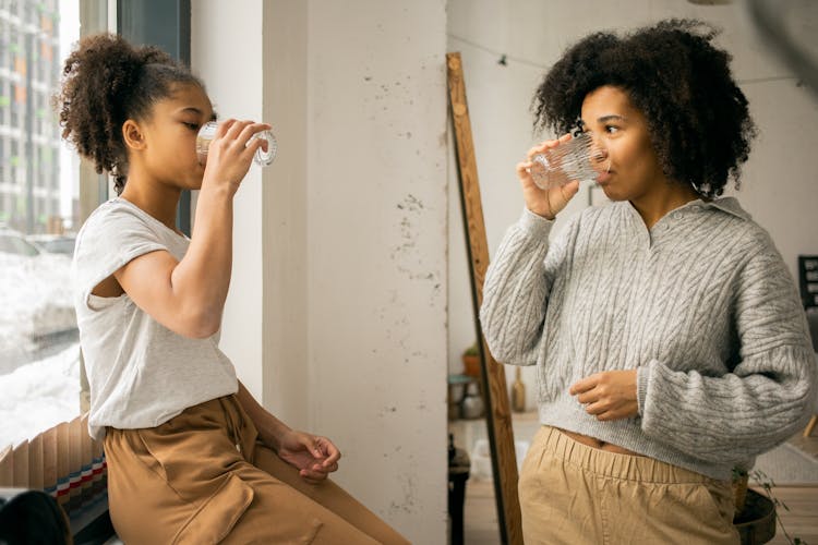 Black Woman With Daughter Drinking Water