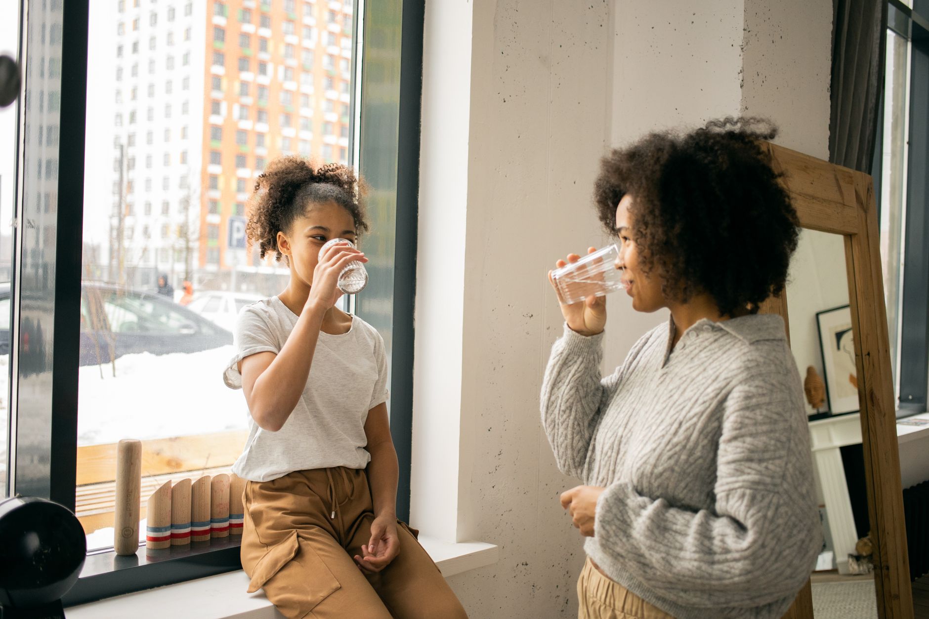 mother and daughter drinking water together indoors showing healthy hydration habits