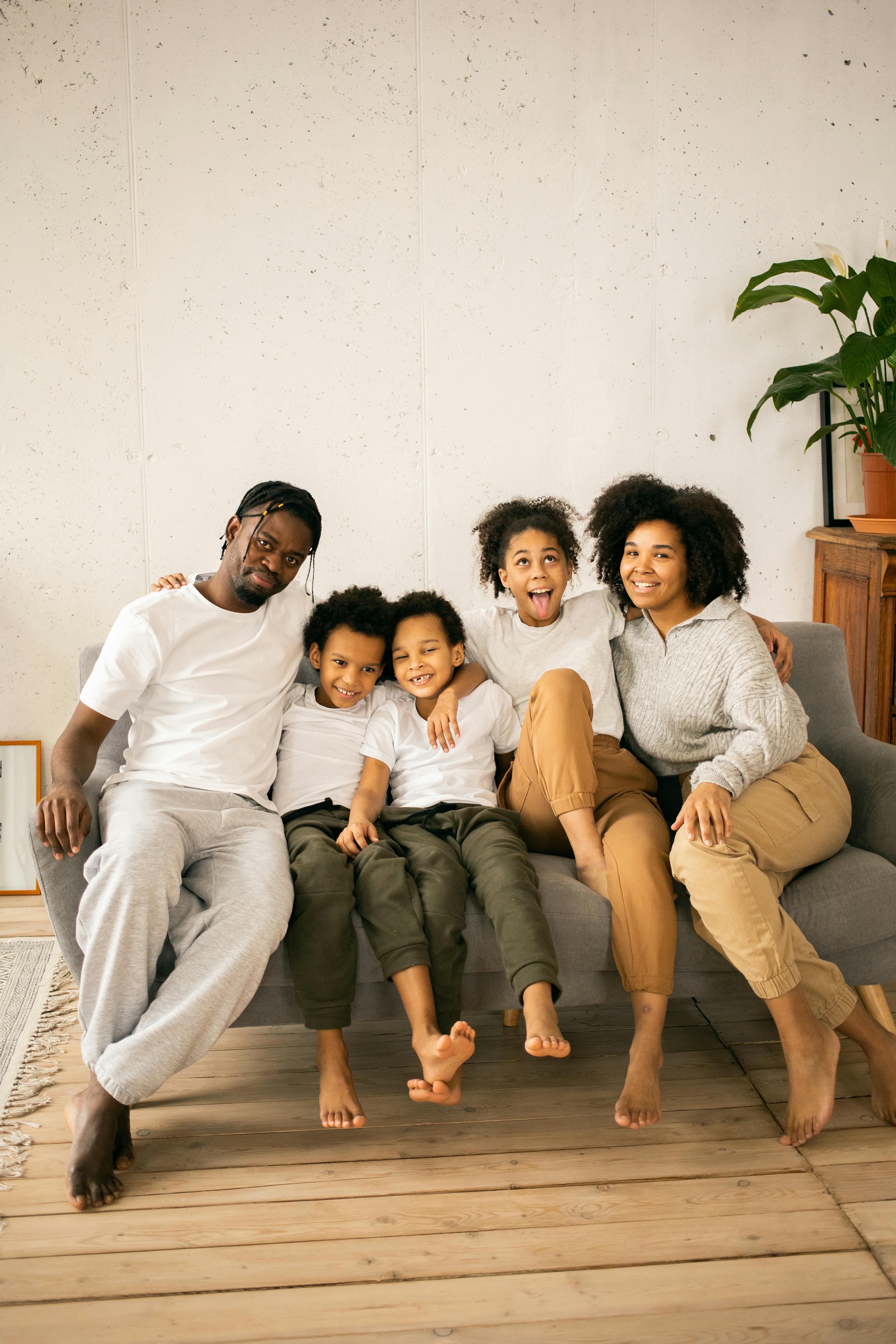 joyful black family sitting together on couch in room