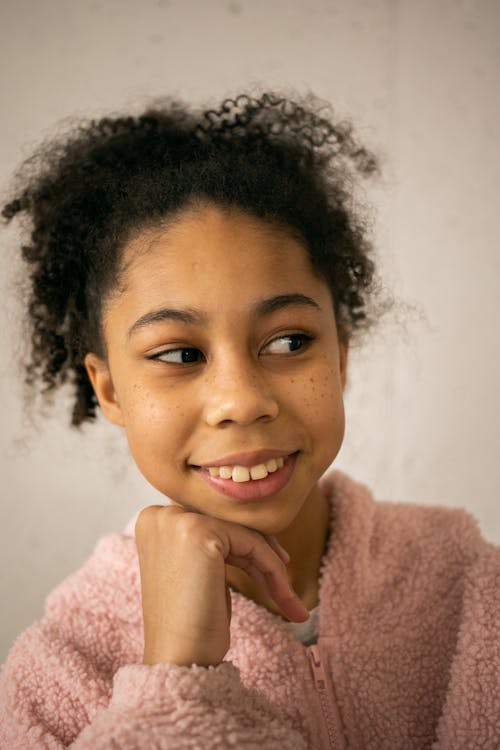 Cheerful black girl near wall