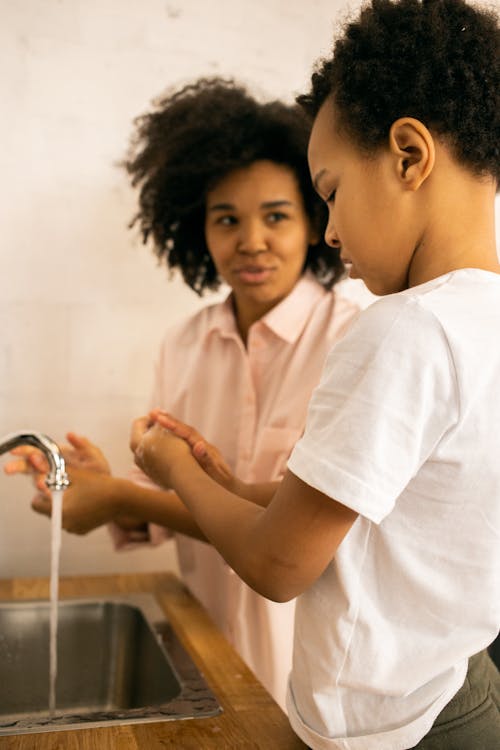 Free Black mother and son washing hands at sink Stock Photo