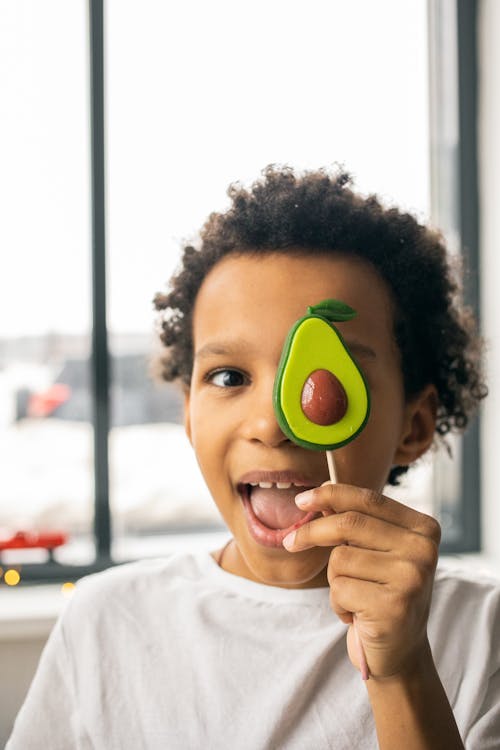 Free Happy black boy with avocado lollipop Stock Photo