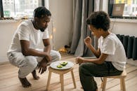 Black man with son near plate with avocado and similar lollipop