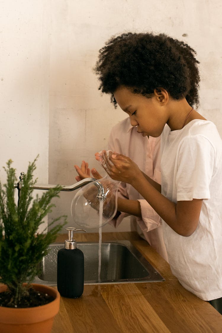 Unrecognizable Black Mother With Son Washing Hands In Kitchen