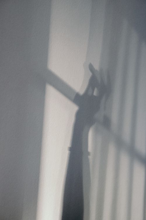 Free Ethereal shadow of a hand reaching up cast on a wall, creating a mysterious silhouette effect. Stock Photo