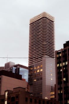 Dramatic view of a modern skyscraper in an urban cityscape at dusk.