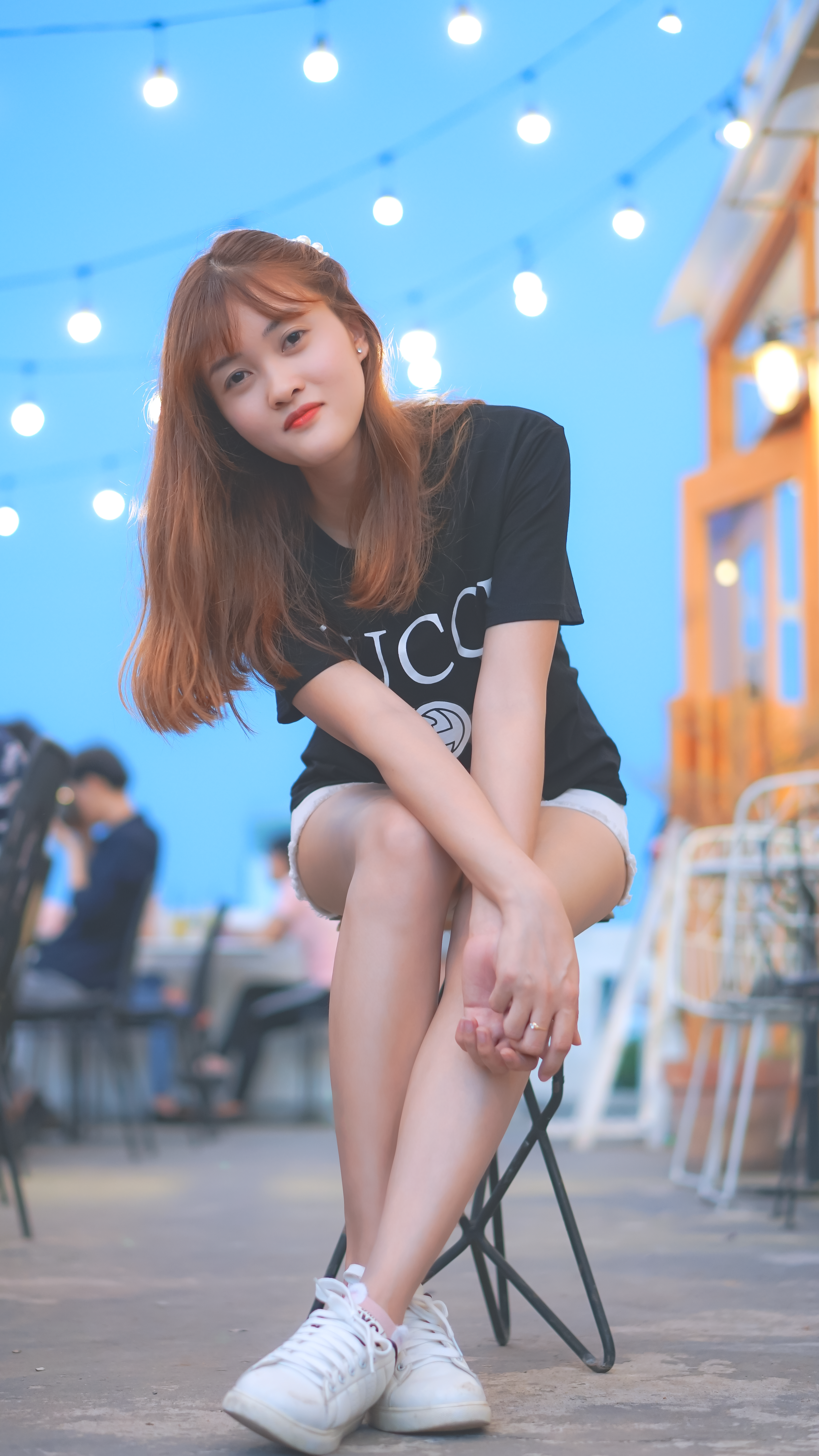 Stylish young woman posing at an outdoor cafe in Ho Chi Minh City, exuding modern elegance.
