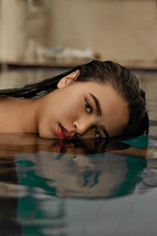Free Elegant portrait of a woman floating in water with her reflection, capturing serene beauty and allure. Stock Photo
