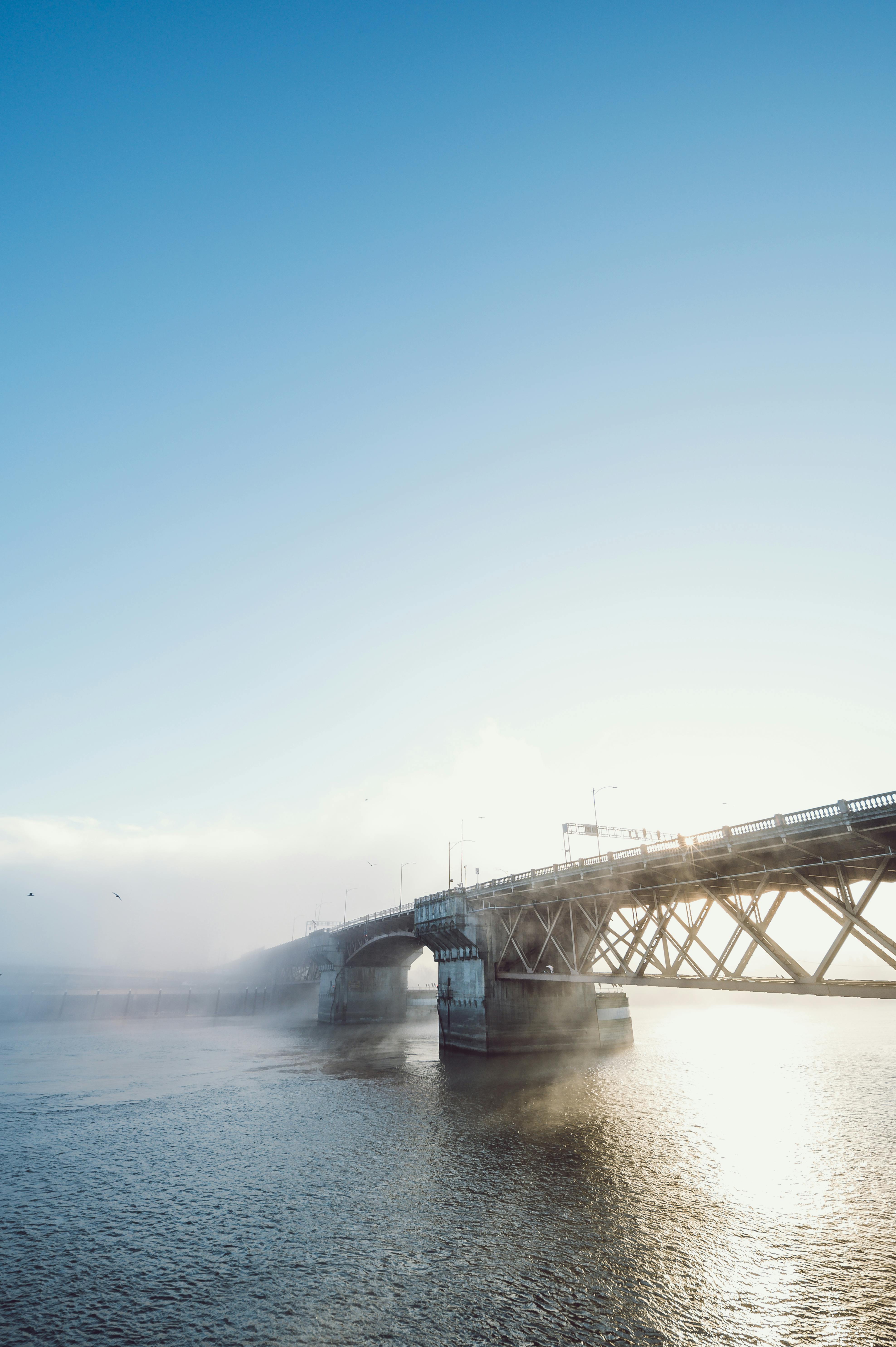 Picturesque scenery of arched bridge crossing rippling river against cloudy blue sky at sunset