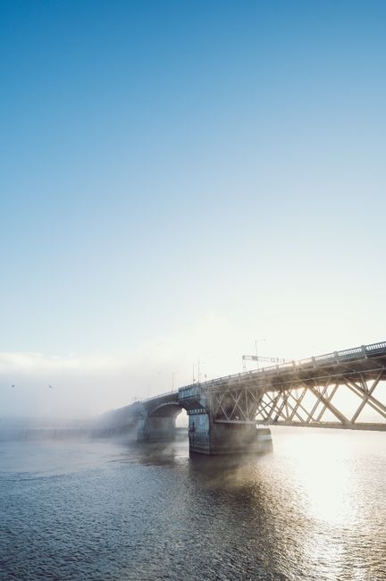 Picturesque scenery of arched bridge crossing rippling river against cloudy blue sky at sunset