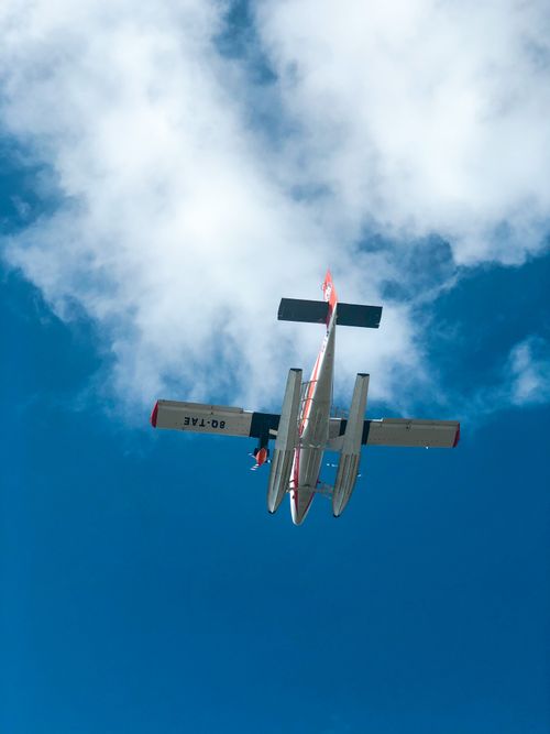 Free A light aircraft captured from below flying against a vivid blue sky with scattered clouds. Stock Photo