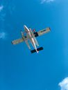 From below of contemporary aircraft with slender floats flying high in air on blue sky with clouds on sunny day