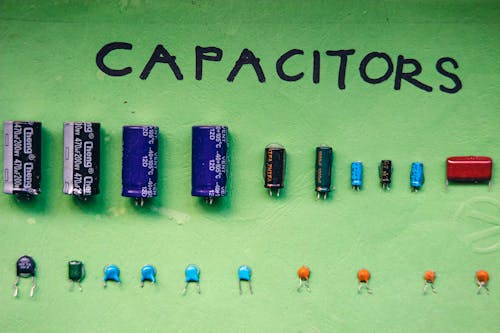 Top view layout of various capacitors for storing electrical energy of different sizes and capacities arranged on green background with inscription