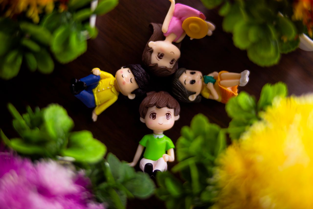 top view cute small figurines of couples arranged on table near bloomi