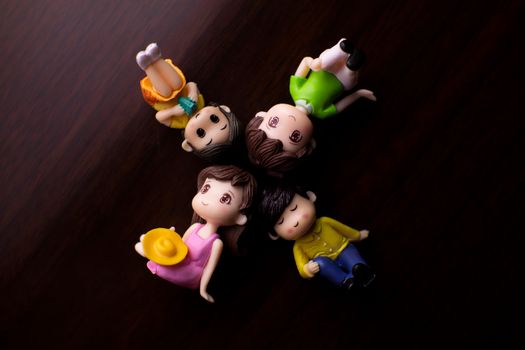 Top view colorful small figurines of cute couples with boys and girls arranged on desk in light room at home