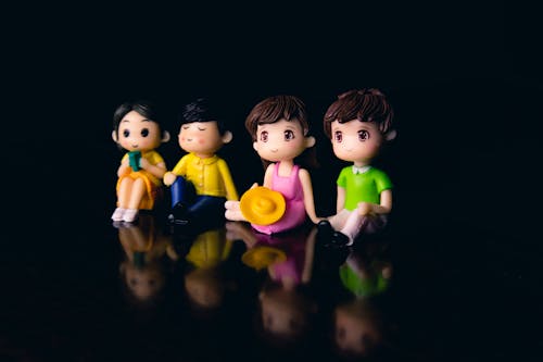 Free Small colorful figurines of couples with boys and girls placed together on surface with reflection in room on blurred background Stock Photo