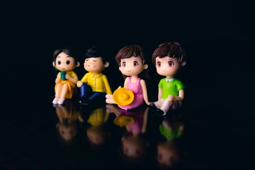 Small colorful figurines of couples with boys and girls placed together on surface with reflection in room on blurred background