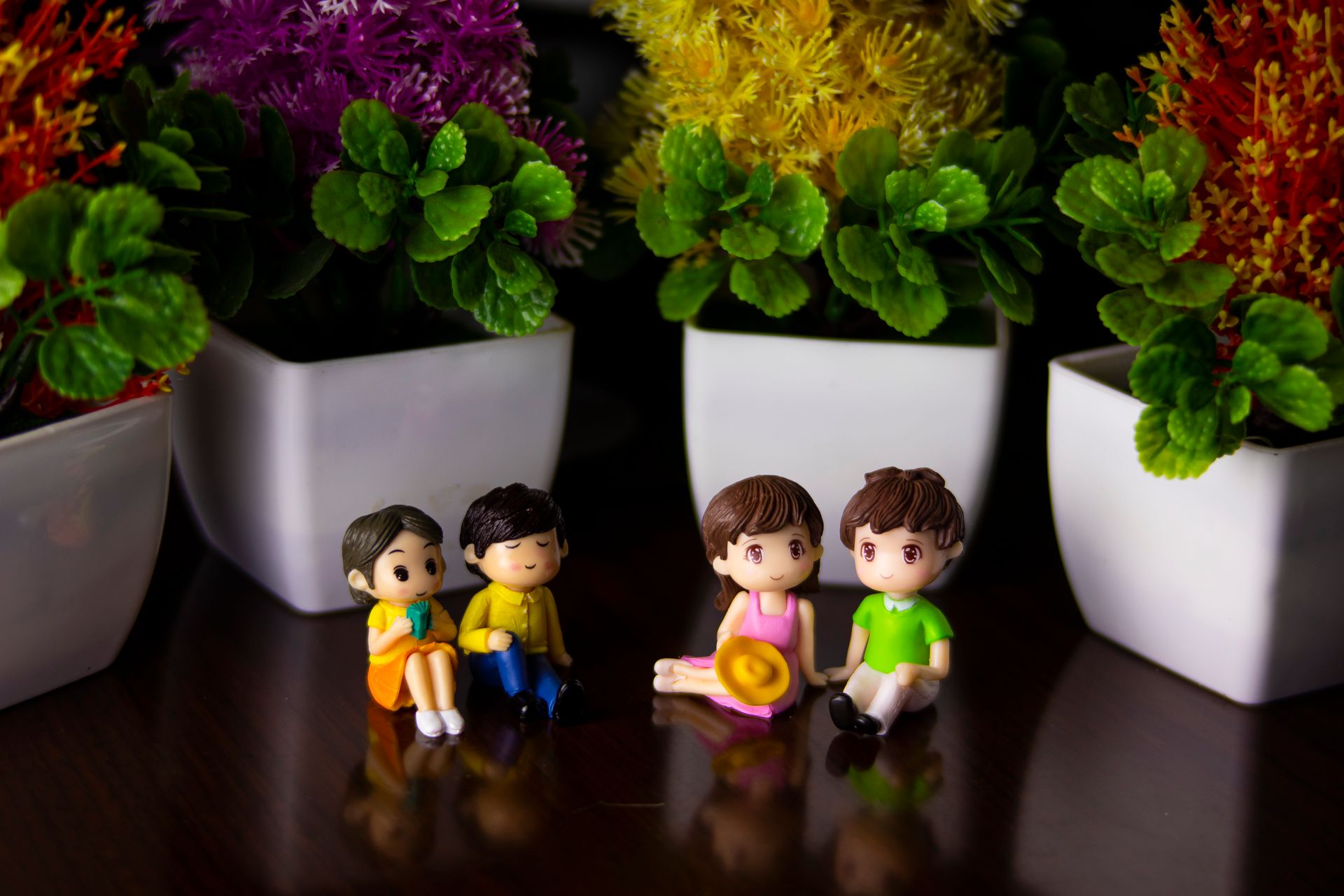 Adorable miniature couple figurines sitting among vibrant potted plants in a modern indoor setting.