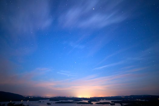 宁静的天空景观中，星星、发光的地平线和黄昏时的条纹云点缀其间