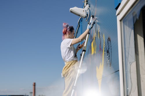 Free A Woman Doing a Graffiti on a Wall Stock Photo
