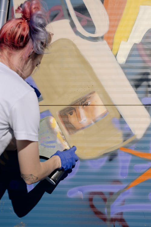 Unrecognizable woman painting graffiti on wall on street
