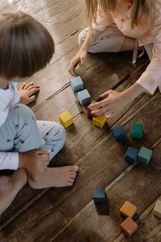 Top view of children playing with colorful blocks on a wooden floor, highlighting creativity and fun.