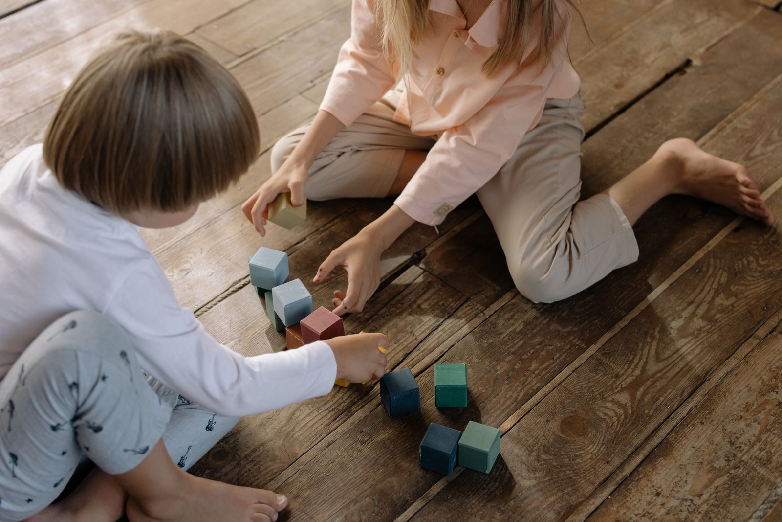 Children building together with colorful wooden blocks during creative play
