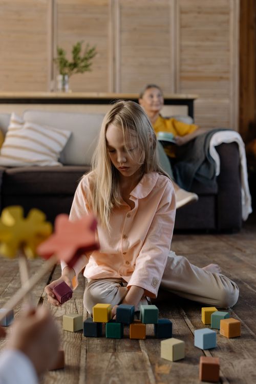 Free Girl playing with colorful blocks indoors, creating a calm and focused atmosphere. Stock Photo