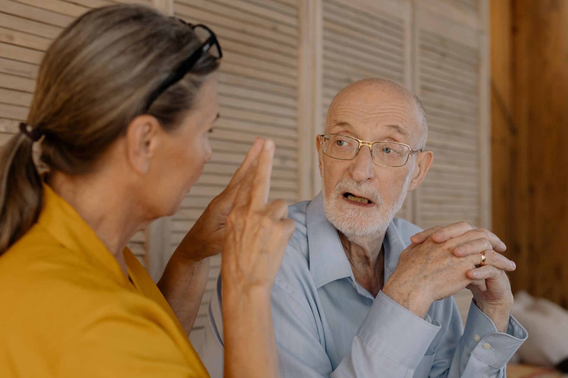 Elderly couple having an engaging conversation indoors, showcasing connection and emotion.