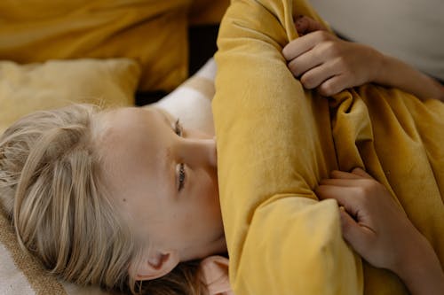 A Kid Covering Her Mouth with a Pillow 