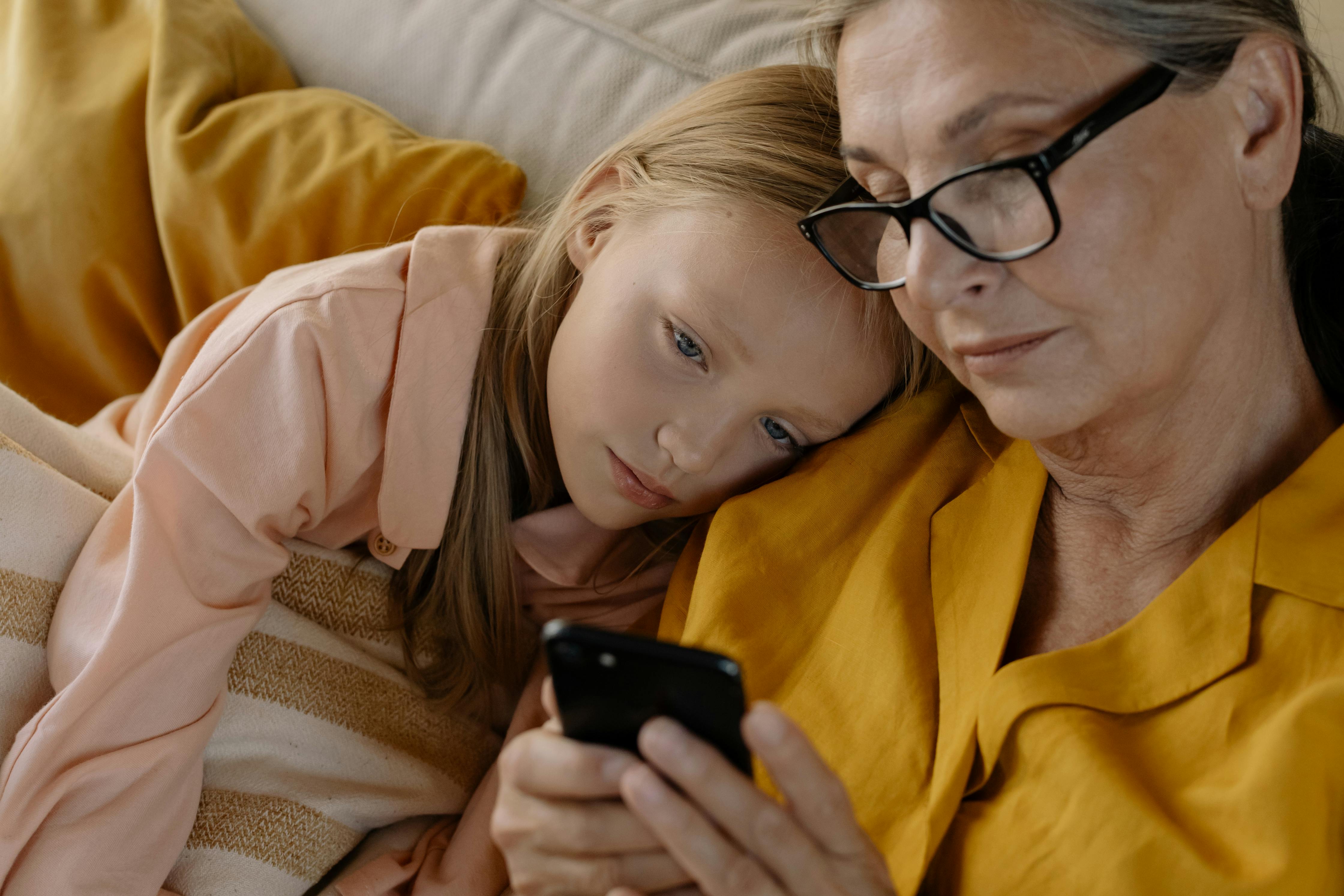 close up photo of elderly woman and a girl looking at the screen of a cellphone