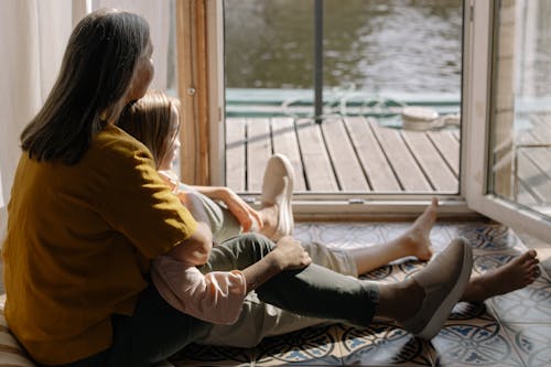 Free Woman in Yellow Top Sitting on the Floor with her Grandchild Stock Photo