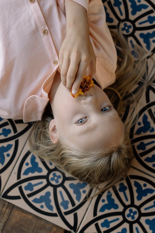 Free Girl in Pink Button Up Shirt Eating while Lying Down Stock Photo