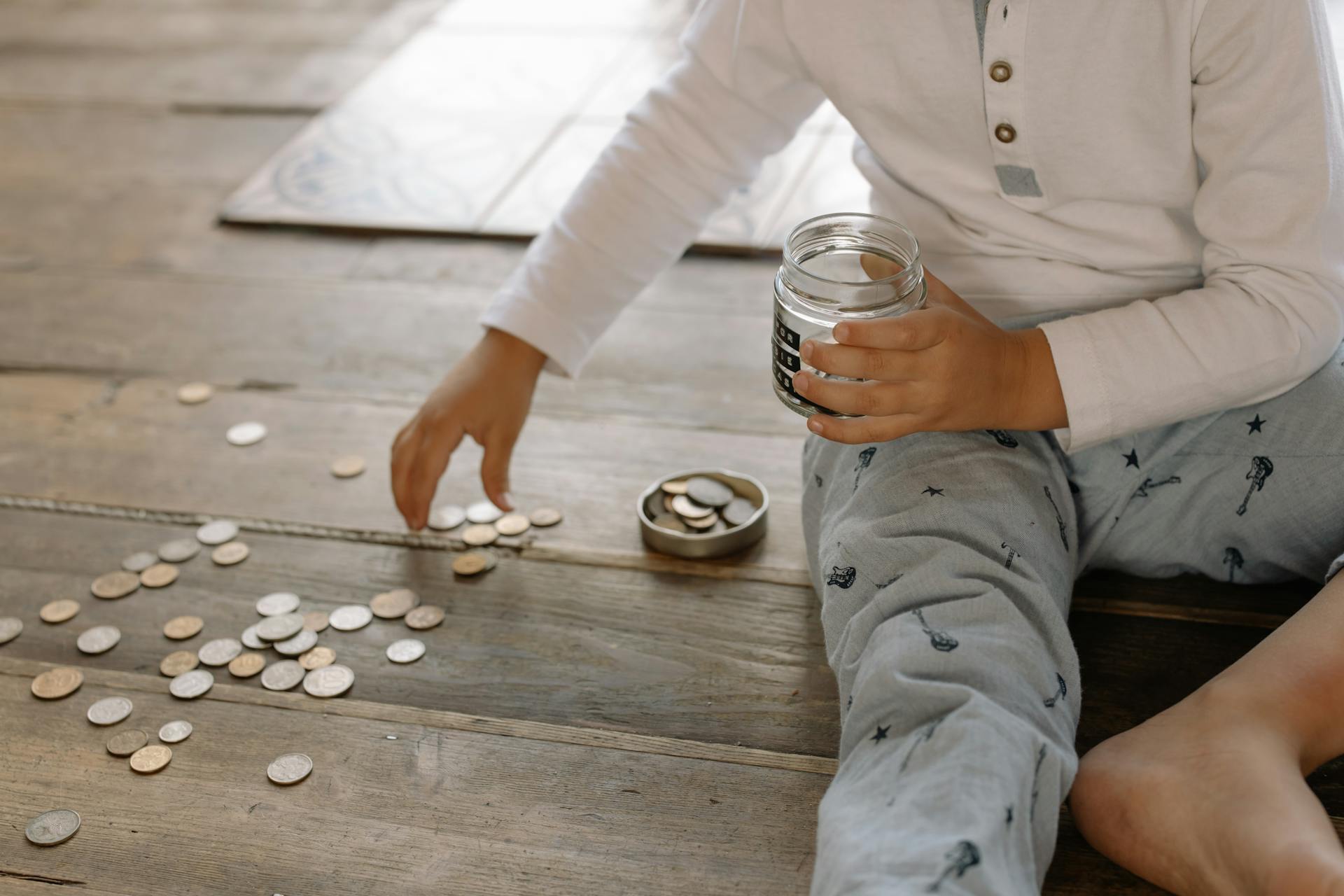 Child Putting Coins into Glass Jar