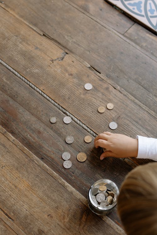 Free A Person Picking the Coins on the Wooden Flooring Stock Photo
