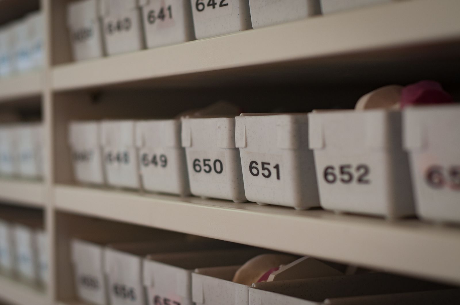 Close-up of numbered storage containers lined up on a shelf, each labeled with a different number