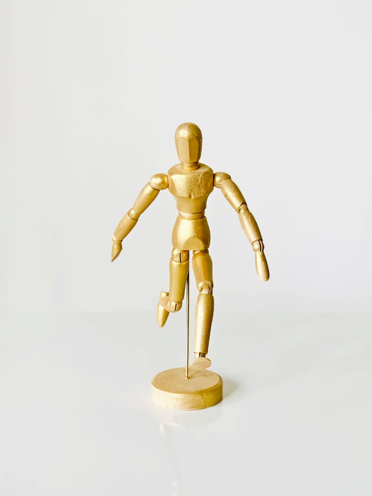 Photograph Of A Gold Mannequin On A White Surface