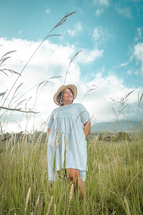 Free Woman in White Dress Standing on Green Grass Field Under Blue Sky Stock Photo