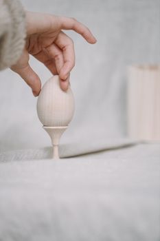 A hand holding a wooden egg on a minimalist background, perfect for Easter decor ideas.